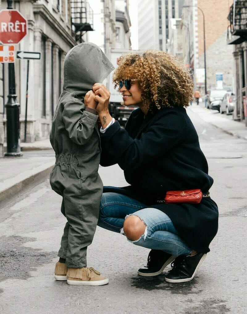 A woman advocating for healthcare equity while kneeling on the street with her son.