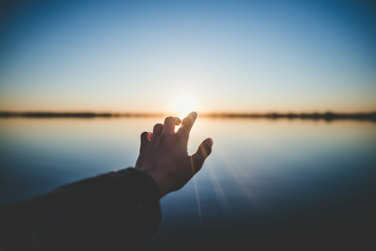 A person's hand extending towards the sun, symbolizing hope and youth wellness.